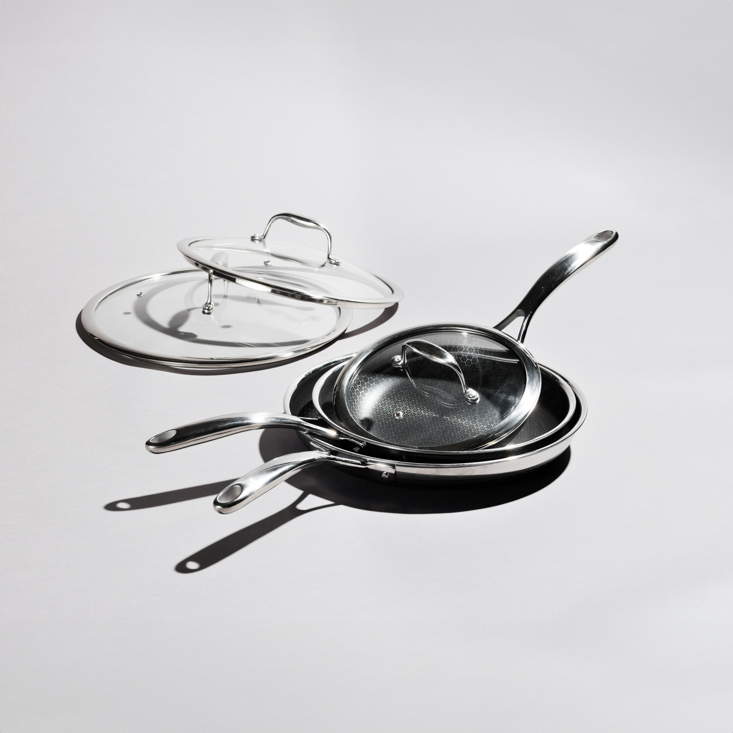 HexClad hybrid cookware featuring a stainless steel pan with a transparent glass lid. The pan's unique design ensures even heating and non-stick cooking for chef-quality results at home.